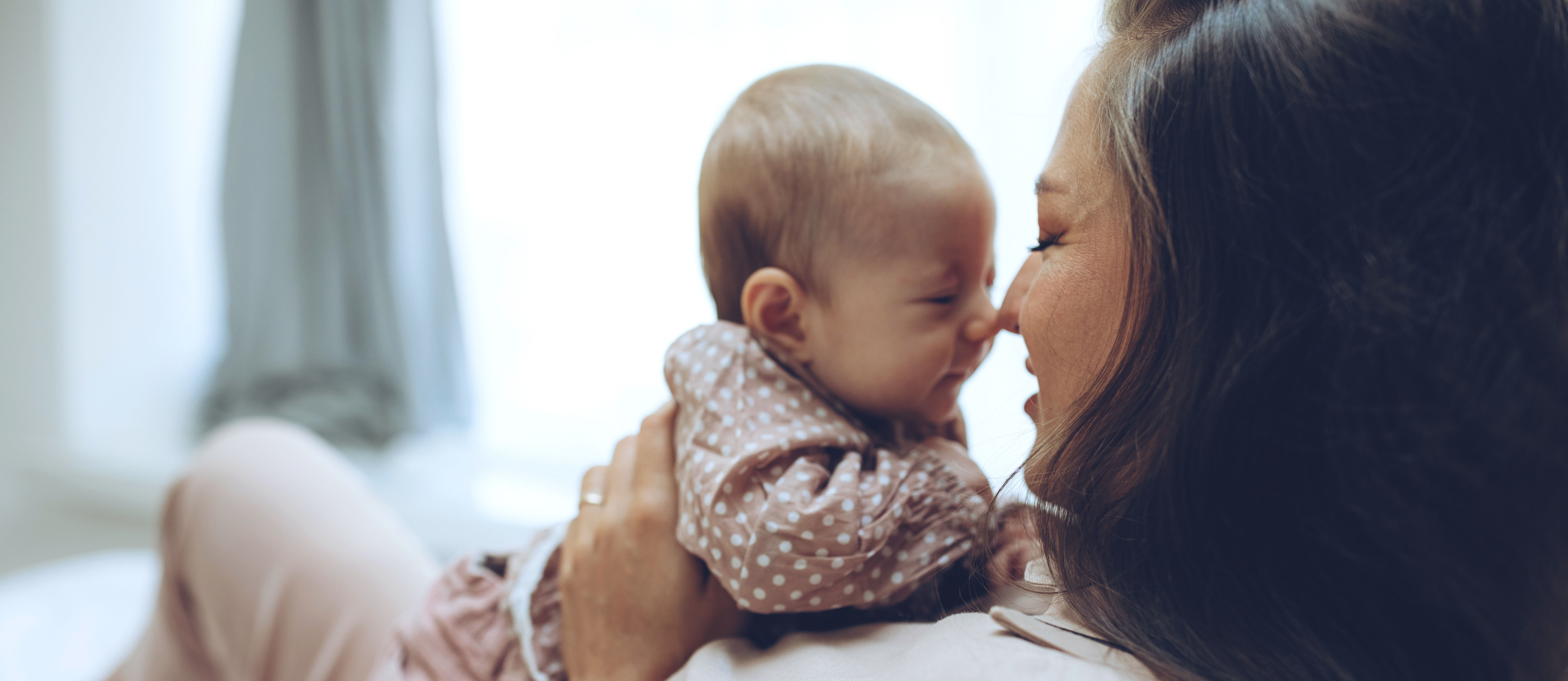 a photo of a mom holding her new baby close to her face, touching nose to nose