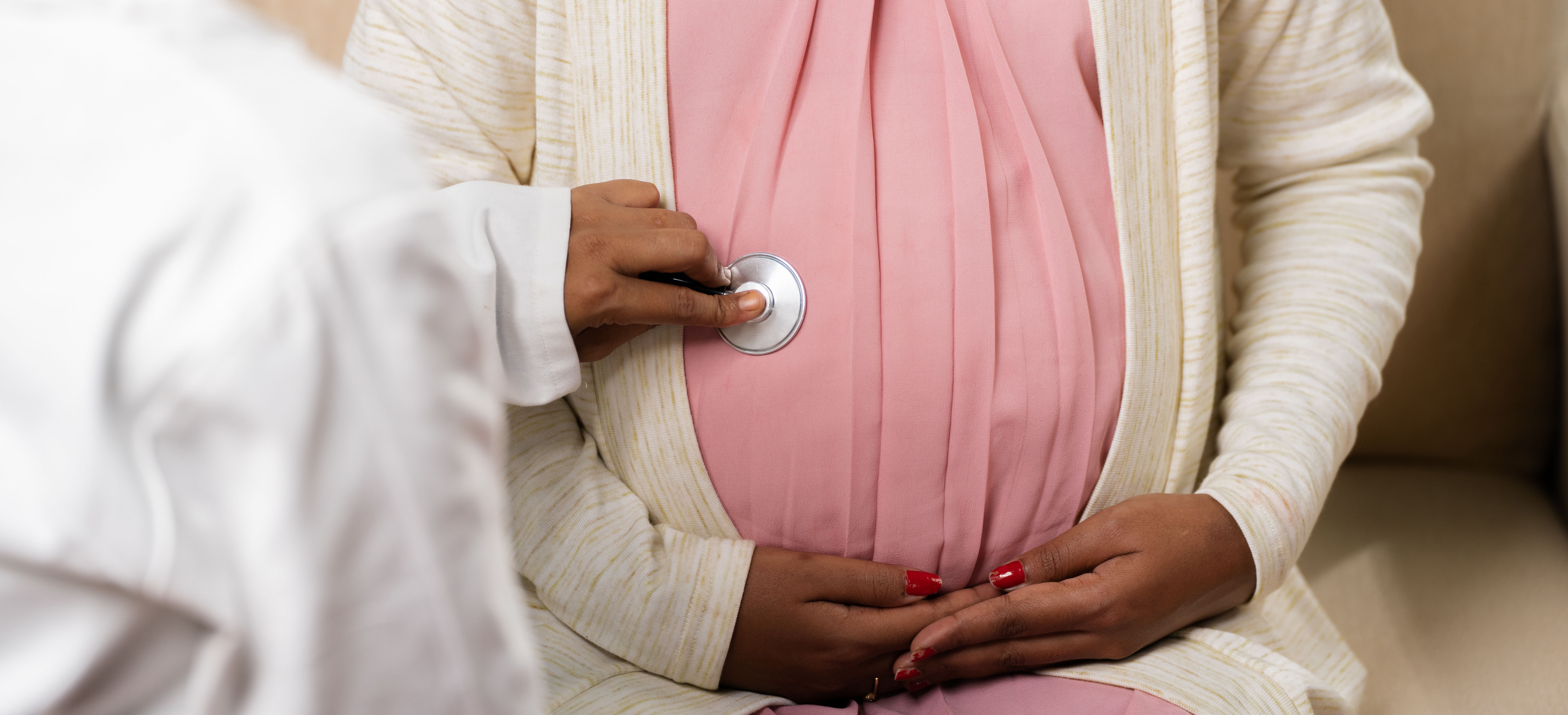 a photo of a pregnant woman holding her stomach, a doctor is holding a stethoscope up to her belly