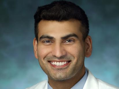 a headshot of Dr Khyzer Aziz smiling at camera in a white lab coat