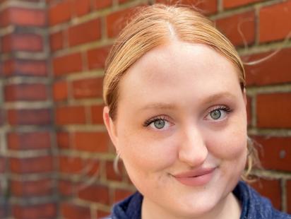 a headshot of Sarah Clifford smiling at the camera in front of a brick wall