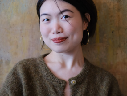 A young woman in a green sweater in front of a brown background