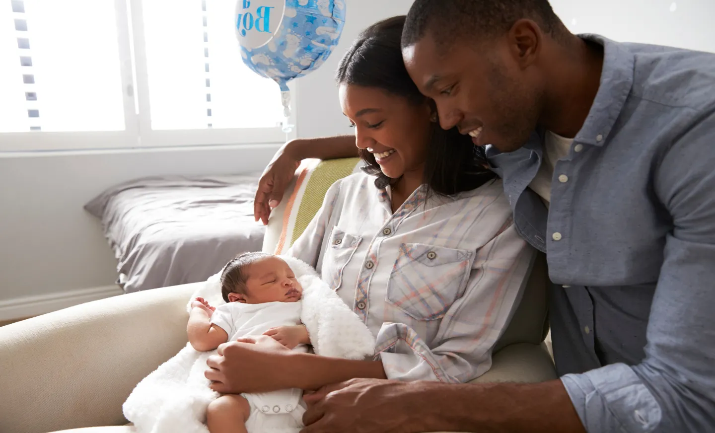 A photo of a husband and wife holding their newborn in the hospital