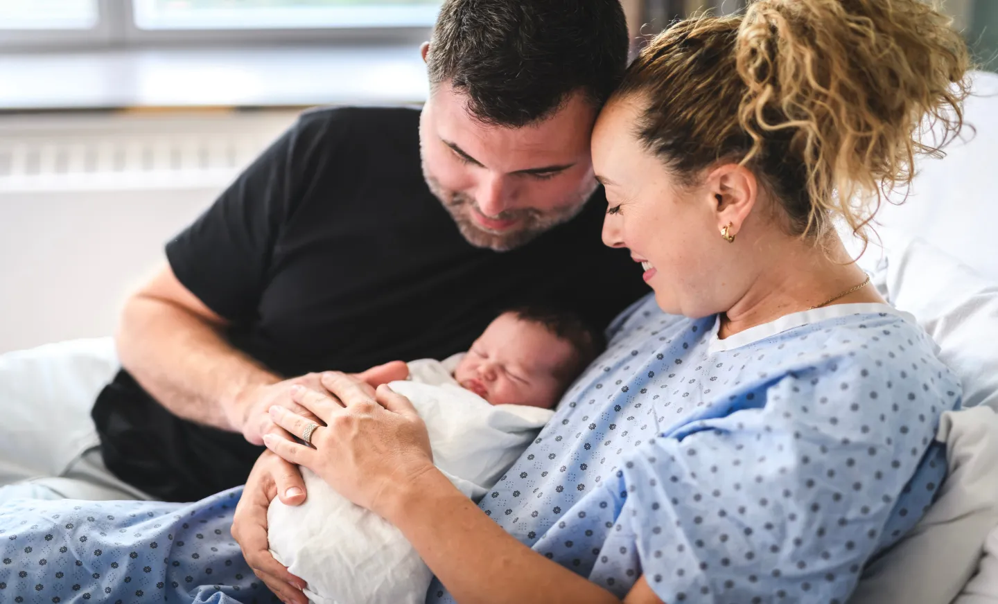 a mom and dad hold their new baby in the hospital