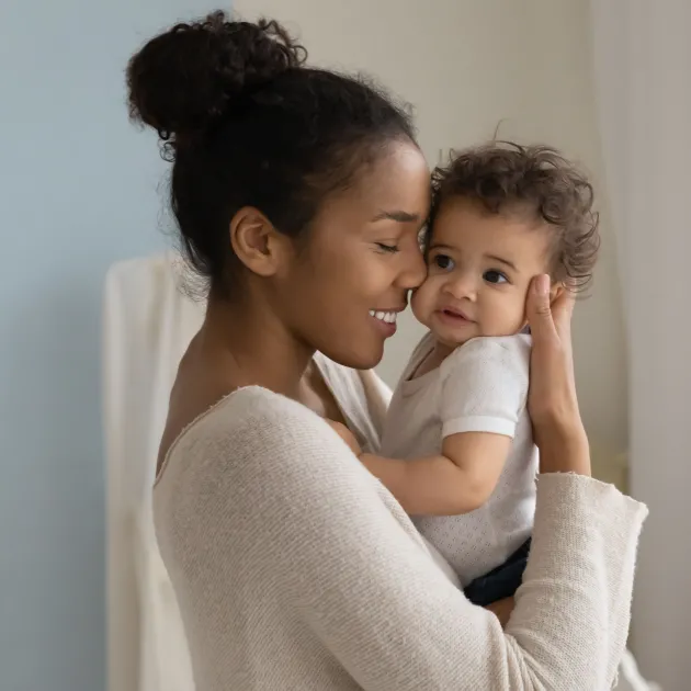 A mom holds her smiling young infant