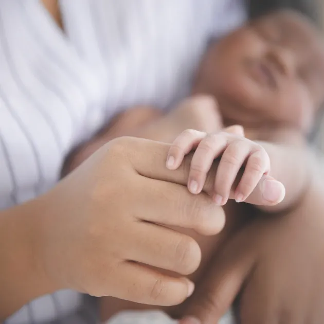 baby holding moms finger