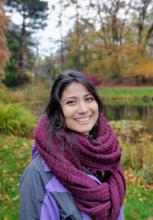 A photo of a young woman with a purple scarf in a natural landscape